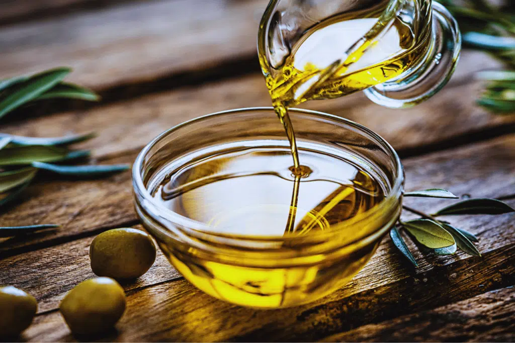 olive oil being poured from a jug to a bowl