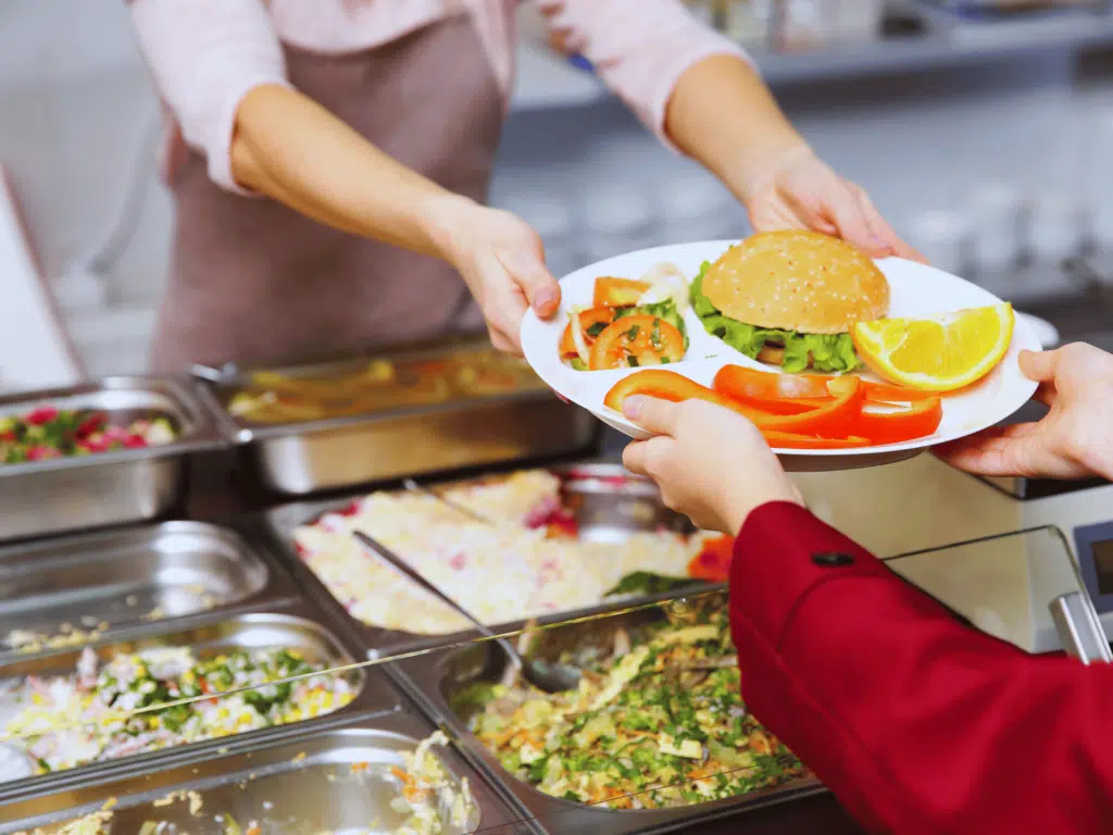 school cook handing out dinner to puplis at a school